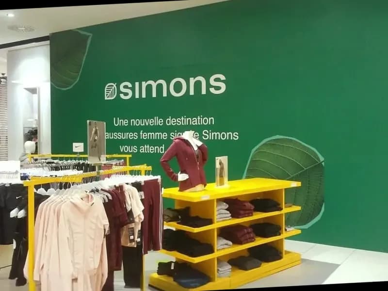 Mur intérieur vert avec logo Simons et motifs de feuillage en magasin