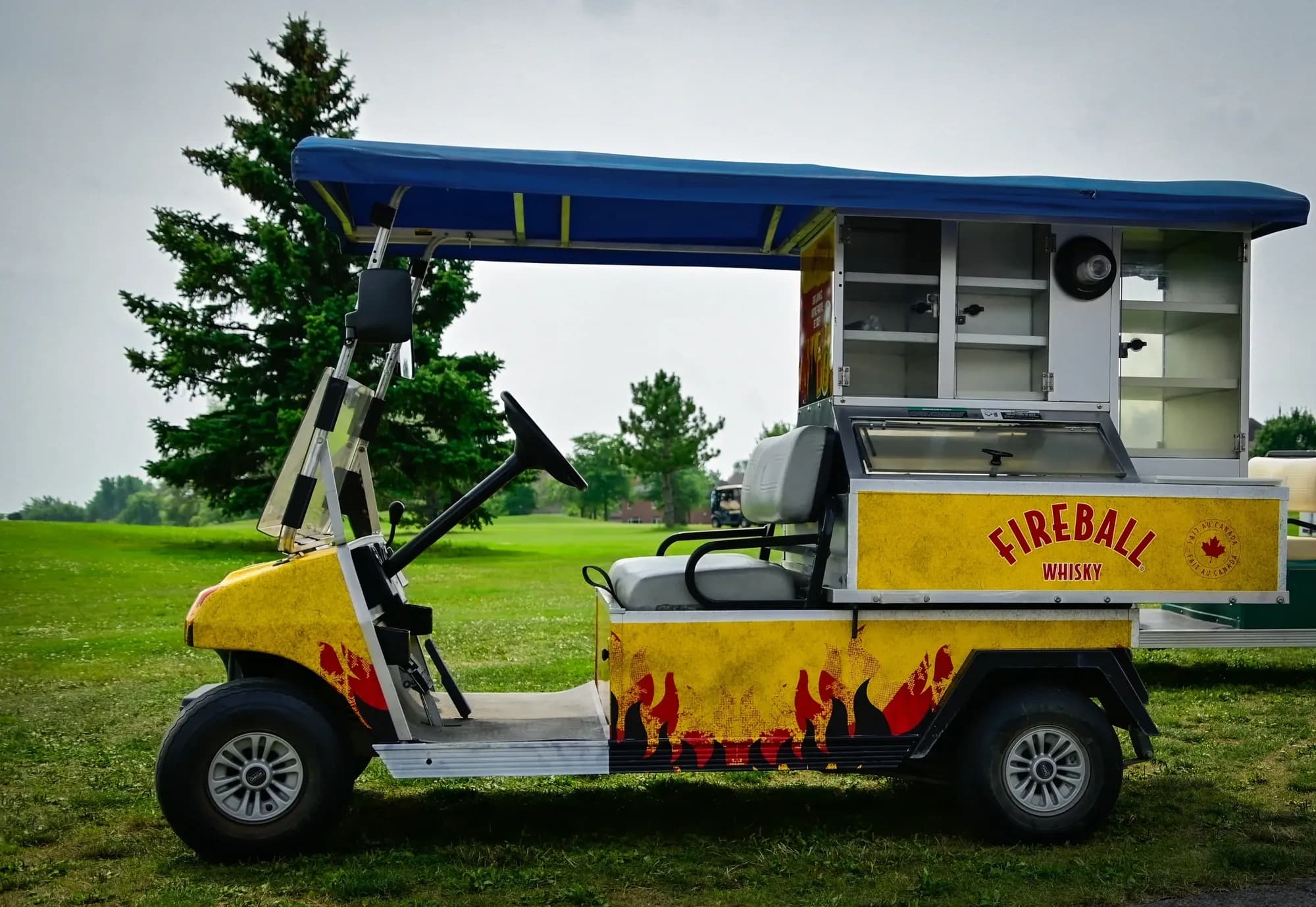 Voiturette de service habillée aux couleurs de Fireball Whisky sur un terrain de golf